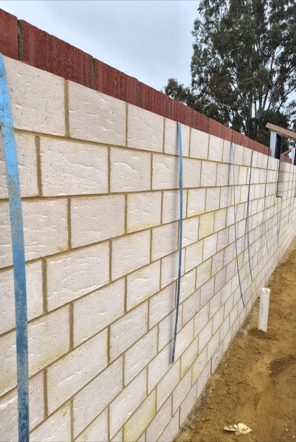 Long run of cream block boundary wall laid level along a residential site