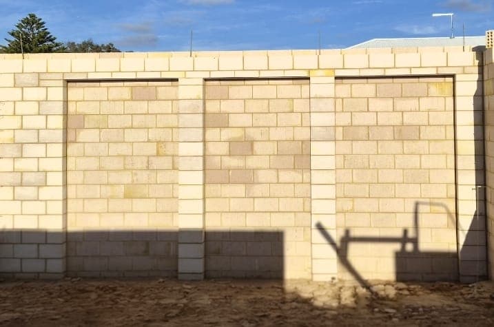 Finished cream limestone-look boundary wall with recessed panels between full-height piers